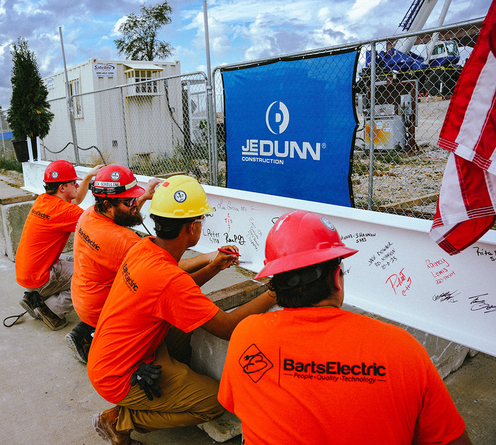 Construction workers signing steel beam at ceremony