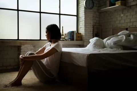 Stock photo - young women sitting thoughtfully by bed