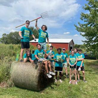 A team of volunteers posing around a bale of hay