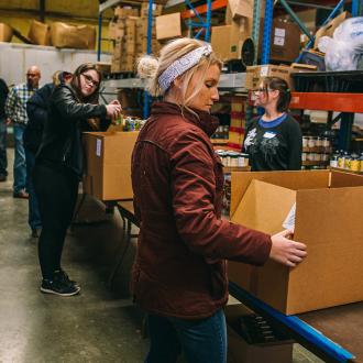 Employee boxes items at Just Food, Lawrence KS