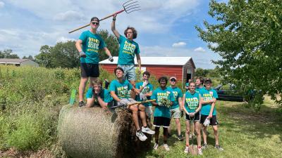 Group photo around a bail of hay at farm