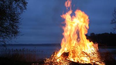 A large bonfire in foreground of darkening night sky
