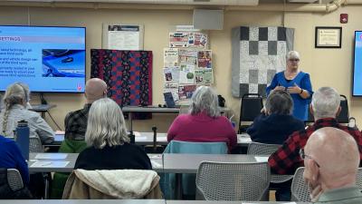 Older individuals sit listening to a presentation