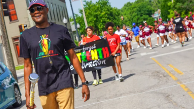 A man leads the annual Juneteenth parade down Mass Street