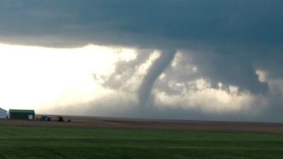 Tornado touching down on farmland with barn buildings on the left side